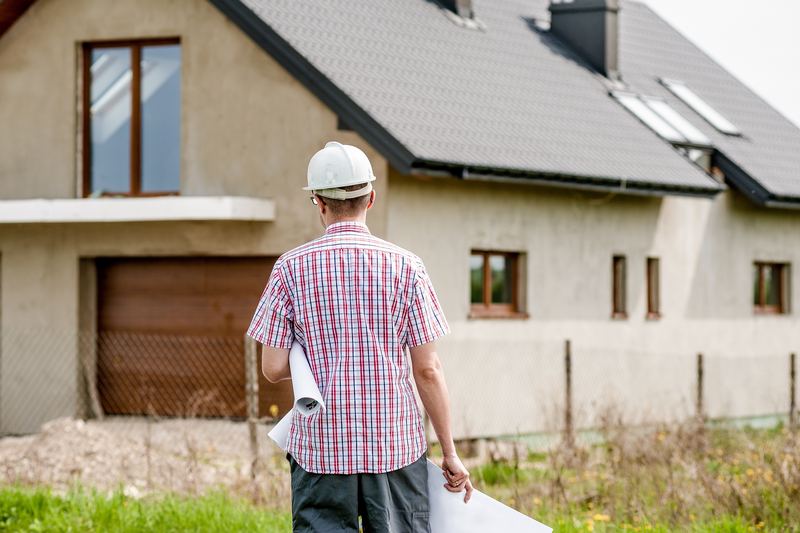 Artisan casqué devant une maison en cours de chantier